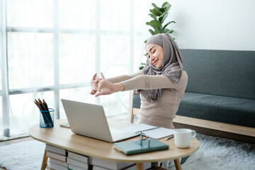 Young business Asian Business muslim woman in hijab using a tablet, Sitting near the window in the living room. 