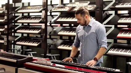 Young man choosing a piano or synthesizer in a musical instrument shop. Buying a midi keyboard in a store.