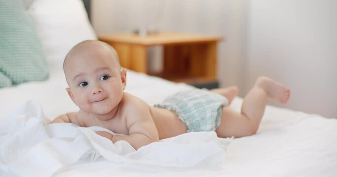 Adorable baby boy lying on stomach in bed