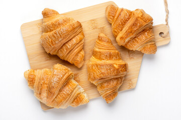 French croissants for breakfast. Freshly baked croissants on cutting board, isolated on white...