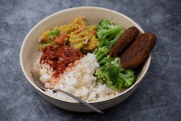 Vegan cutlets made of seitan. along with rice, kimchi, side veggies. Vegan bowl.