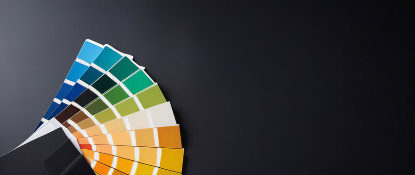 Color guide close up. Assortment of colors for design. Colors palette fan on black concrete wall background. Color palette guide circle. Coloured swatches. Open paint sample colors catalogue. Rainbow