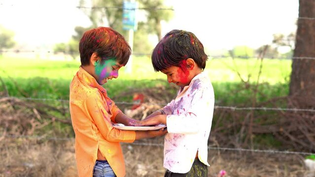 Two indian boy applying color to each other and celebrating holi festival.