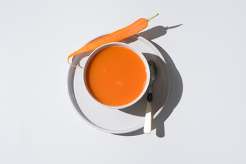 Sopa de zanahoria en un plato sobre fondo gris y blanco. Vista superior - obrazy, fototapety, plakaty