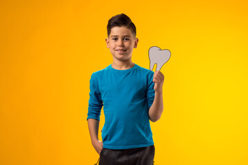 Child boy holding papercraft tooth. Dental health concept