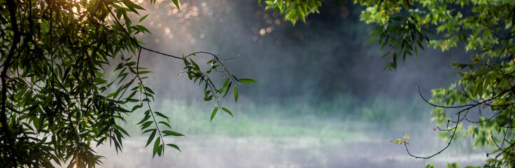 Fog over the river in the morning. The sun rises over the river in summer. There is fog on the...