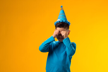Crying kid boy wearing blue cone hat having mournful upset facial expression