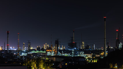 Fototapeta na wymiar Night cityscape and oil refinery, petroleum oil yard, tank storage field. Crude oil, natural gas. Nice lighting cover the city. Business and industrail, import and export, international 