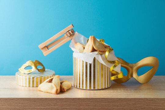 Jewish holiday Purim concept with hamantaschen cookies and golden carnival mask on wooden table over blue background