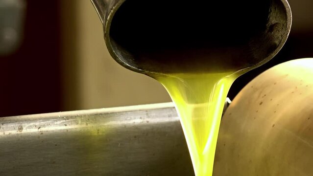 closeup footage of pure extra virgin olive oil falling into steel tank: oil mill