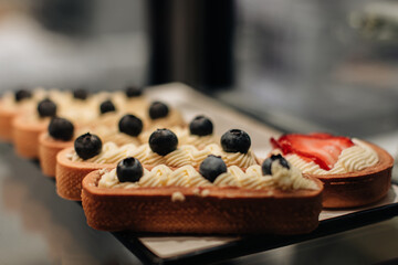 Sweet cake with fresh blueberries and butter cream. Delicious dessert on a stand in a bakery store