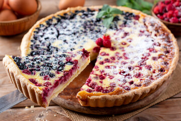 Delicious blueberry pie with raspberries on a wooden table. Homemade baking