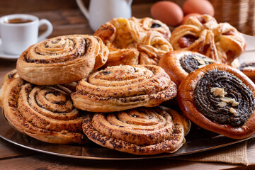 Table with various buns, rolls, cakes and coffee cup on a wooden table. Homemade bakery concept for background and wallpaper.