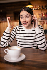 Smiling brunette woman talking on the phone. Girl in conversation using mobile phone while laughing. Lady having fun during a funny conversation call.