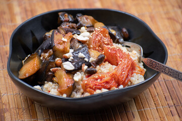 Korean rice and kimchi, eggplant served in black bowl, bamboo mat