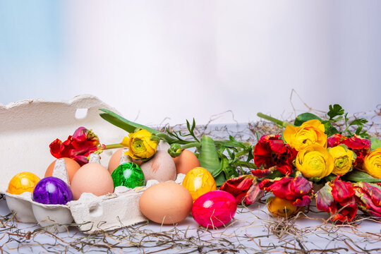 Bunte Ostereier auf einem Tisch mit Bumenstrau&szlig; als Postkartenmotiv zu Ostern