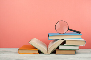 Open book, hardback colorful books on wooden table. Magnifier. Back to school. Copy space for text. Education business concept.