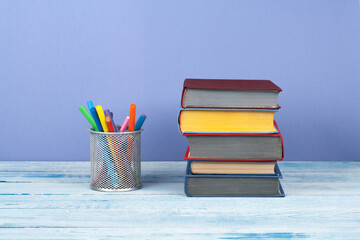 Book stacking. Open book, hardback books on wooden table and blue background. Back to school. Copy...