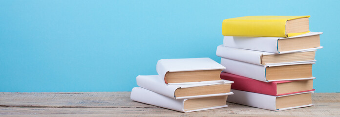 Books stacking. Books on wooden table and blue background. Back to school. Copy space for ad text. panorama, banner.