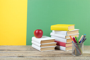 Books stacking. Books on wooden table and green, yellow background. Back to school. Copy space for...