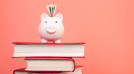 Piggy bank in glasses and books on Orange background. open book. Tuition payment. Brainwork. Back...
