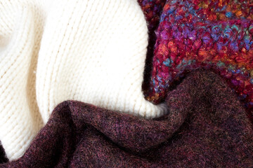 Knitted woolen sweaters. A bunch of knitted winter, autumn clothes, sweaters, knitwear, space for the text.