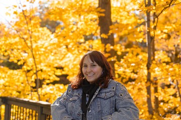 photo of a tourist visiting a natural park during the fall season, with yellow leaves behind her