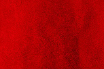 Red background from a natural suede piece of material. Macro photo of red velvet texture.
