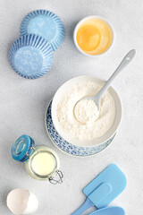 Baking ingredients: flour, eggs, yolk, on a white table.