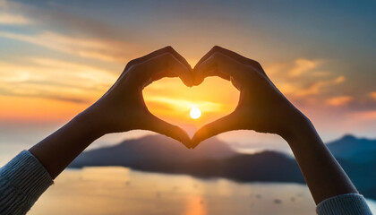 Silhouetted hands of caucasian woman forming heart shape at sunset, symbolizing love, hope, and connection