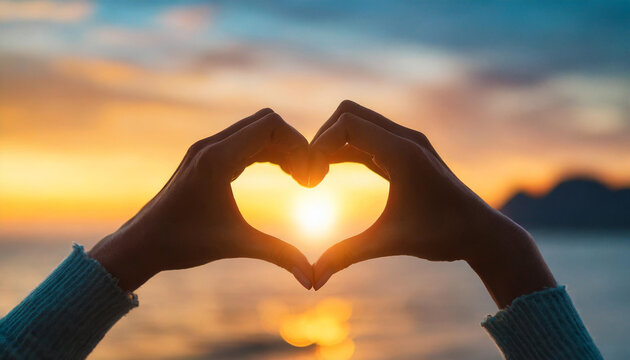 Silhouetted hands of caucasian woman forming heart shape at sunset, symbolizing love, hope, and connection