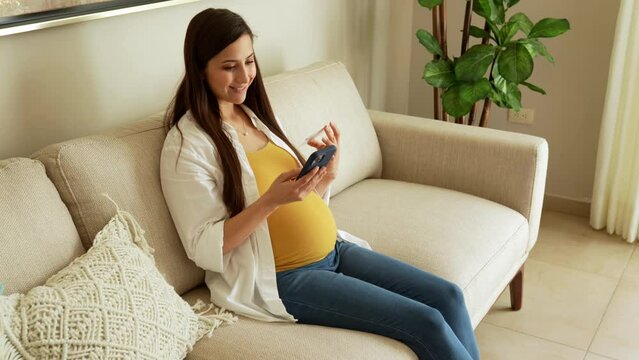 Cute pregnant woman taking a selfie while showing her sonogram to post on social media