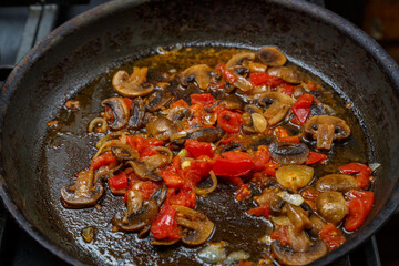 Champignon with tomato and onion is stewed in a frying pan