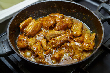 Chicken pieces in a sauce with paprika and turmeric in gravy in a frying pan