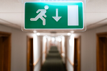 Shallow focus of a generic Fire Escape sign seen hanging from the ceiling of a hotel lobby in the...