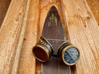 Close up of old wooden Arlberg ski and ancient ski googles on facade of mountain hut. Alpine decor,...