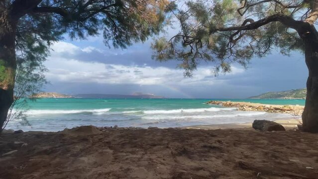 A beach with a rainbow and a stormy sky. Rainbow over the stormy sea after rain with lightning, calm sea in the foreground, Beach cove with dramatic clouds forming a rainbow over the blue ocean