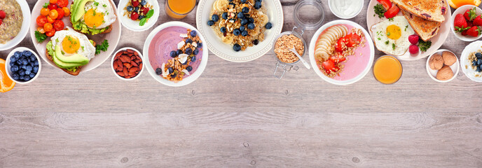 Healthy breakfast or brunch top border on a wood banner background. Overhead view. Avocado toast,...