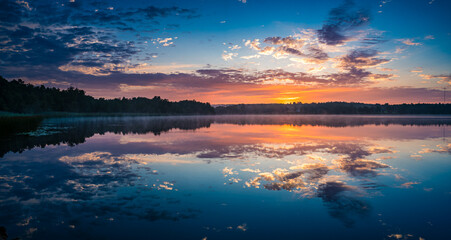 Serene Sunrise Over Lake With Reflective Waters and Radiant Skies
