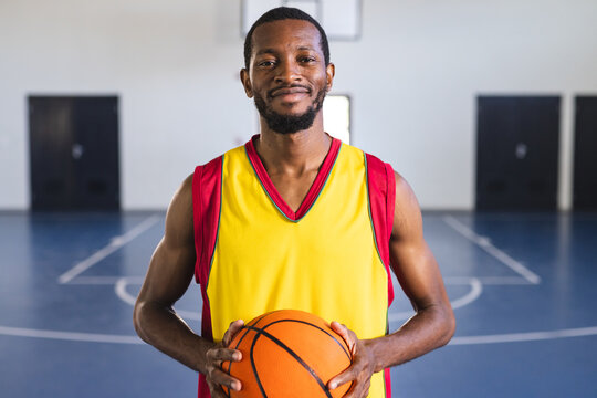 African American man holds a basketball in a gym