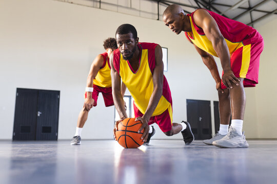 African American men playing basketball indoors, with copy space