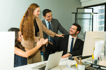 Office workers recognizing a man's work in the office and showing their support
