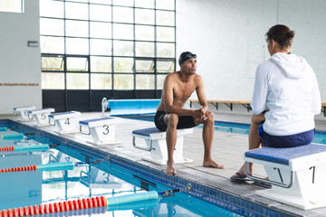Swimmer and coach discuss strategy poolside, with copy space