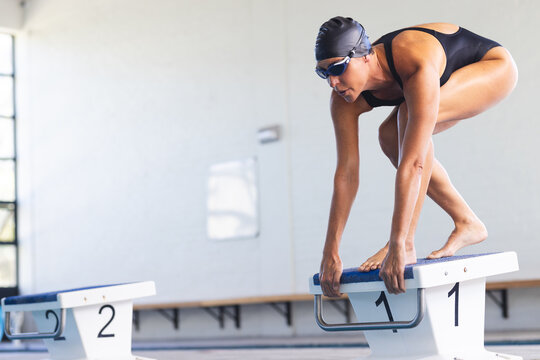 Caucasian female athlete swimmer prepares to dive into a pool at a competition