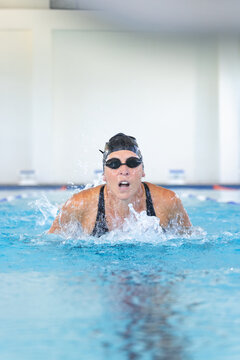 Caucasian female athlete swimmer swims vigorously in an indoor pool