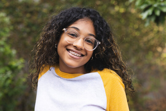 A teenage girl smiles brightly outdoors