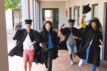 Diverse group of graduates celebrates outdoors, with copy space