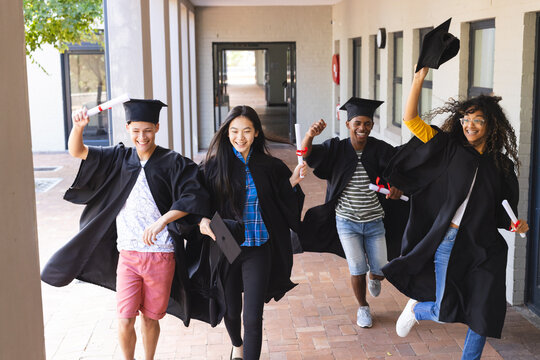 Diverse group of graduates celebrates outdoors, with copy space