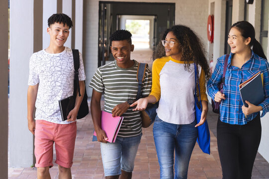 Diverse group of teenagers walking in a high school hallway