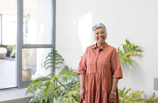 Senior biracial woman stands smiling in a bright home, with copy space